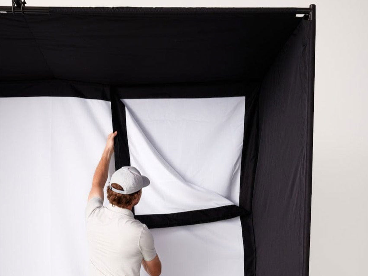 Person setting up a photography studio with black and white backdrops